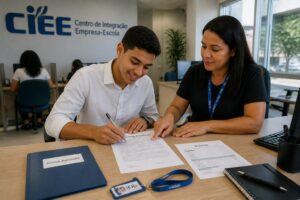 Young Brazilian adult signs a CLT work contract at a CIEE office while an HR advisor points to the document on the desk.